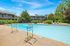 Inviting outdoor pool area with lounge chairs and playful water features, surrounded by lush greenery and modern apartments.