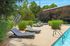Serene outdoor pool area with modern loungers surrounded by lush greenery, perfect for relaxation and leisure.