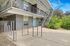 Modern two-story apartment building with sleek metal railings, lush greenery, and vibrant blue doors.