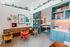 Chic apartment interior showcasing vibrant art, cozy seating, and elegant shelving in a modern communal area.