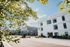 Modern apartment complex with stylish architecture, lush greenery, and ample natural light reflecting off the sleek white and gray exteriors.