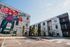 Chic modern apartment complex with vibrant floral mural and lush landscaping, offering a welcoming urban living environment at First Street Flats.