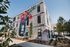 Vibrant modern apartment building with colorful mural facade, surrounded by greenery and clear blue skies.