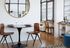 Modern apartment dining area with sleek round table, stylish wooden chairs, and large mirror, offering a bright and inviting atmosphere.
