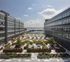 Stunning urban courtyard with lush landscaping, modern seating, and vibrant umbrellas, overlooking waterfront views.