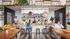 Modern communal kitchen with open shelving, large dining tables, and vibrant greenery, perfect for social gatherings and culinary creativity.