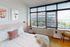 Bright and airy bedroom with chic decor, large windows offering stunning urban views, and cozy accents for a relaxing atmosphere.