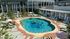 Vibrant outdoor pool area with modern design, featuring lush greenery, comfortable loungers, and playful inflatables for a perfect relaxation spot.
