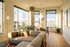 Bright and modern living space with large windows showcasing stunning city views, cozy sectional sofa, stylish dining area, and elegant decor.