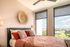 Bright and airy bedroom featuring a cozy bed with plush pillows, modern decor, and expansive windows showcasing a stunning view.