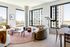 Bright modern living room with panoramic city views, featuring stylish furniture and elegant decor.