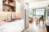 Bright and modern apartment interior featuring a sleek kitchen with open shelving, elegant dining area, and sunlit living space with floor-to-ceiling windows offering breathtaking views.