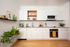 Modern kitchen with sleek white cabinets, stainless steel appliances, and lush green plants adding a fresh touch.