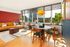 Bright and modern living area with a stylish yellow sofa, vibrant red accent wall, and large windows offering a stunning urban view.