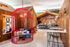 Chic and vibrant seating area with bold red cage-style lounge, colorful cushions, and modern café backdrop.