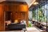 Modern co-working lounge with warm wooden interiors, cozy seating, and abundant natural light surrounded by lush plants.