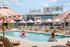 Luxurious rooftop pool with stylish loungers and pink parasols, offering a stunning cityscape view.