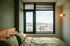 Cozy bedroom with modern bed, large window offering scenic bridge and river view, and soft ambient lighting.