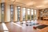 Bright and inviting yoga studio with floor-to-ceiling windows, wooden floors, and artistic feature wall, creating a serene and energizing atmosphere.