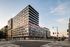 Modern urban apartment building showcasing sleek architecture with expansive windows and a prime city location, now leasing for luxury living.