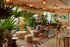 Chic and inviting lounge area filled with lush greenery, stylish wicker furniture, and modern art, creating a cozy and vibrant atmosphere.