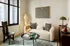 Chic modern living room with cozy beige sofa, vibrant decorative pillows, stylish round coffee table, and elegant floor lamp by large window.