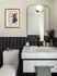 Chic modern bathroom featuring elegant black and white tilework, a stylish vanity with a sleek mirror, and tasteful art decor.