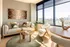 Bright and modern living room with plush seating, artistic wall decor, and expansive city views through large windows.