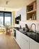 Modern kitchen with sleek design, featuring black countertops, white cabinetry, and a cozy dining area with stunning city views.
