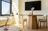 Inviting dining area with modern wooden table, plush chairs, and stylish decor bathed in natural sunlight through large windows.