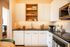 Chic kitchen with modern white cabinets, hexagonal tile backsplash, and sleek black countertop, featuring open shelving and stainless steel appliances.