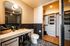 Modern bathroom featuring elegant black tiles, a spacious vanity, and a well-organized walk-in closet.