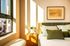 Bright, modern bedroom with stylish green accents, large window, and cozy decor, offering a warm and inviting ambiance.