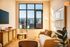 Bright and inviting living room with modern decor, large windows offering cityscape views, and cozy seating.