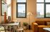 Chic urban living room with warm natural light, cozy orange sofa, modern decor, and expansive city views.