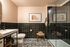 Elegant modern bathroom featuring sleek black tile accents, a glass walk-in shower, and stylish artwork.