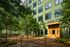 Inviting urban courtyard with lush greenery and modern architecture at Urby apartment building entrance.
