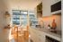Bright and modern kitchen with sleek cabinetry, open shelving, and a sunlit dining area adorned with plants and stylish d&eacute;cor.