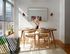 Bright dining area with a chic wooden table set, stylish wall decor, and abundant natural light streaming through modern blinds.
