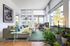 Bright, modern living room with large windows, chic furniture, and lush indoor plants, offering a cozy and inviting atmosphere.