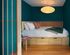 Cozy bedroom featuring a stylish wooden bed frame with under-bed storage, vibrant teal walls, and a chic pendant light for a modern ambiance.