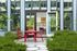 Inviting outdoor patio with vibrant red furniture and lush greenery, leading into a modern interior with an open door.