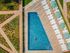 Luxurious outdoor swimming pool surrounded by elegant sun loungers and green umbrellas, set amidst beautifully landscaped gardens.