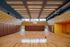 Modern indoor basketball court with polished wooden flooring, vibrant wall design, and ample natural light for an energizing sports experience.