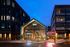 Chic urban development showcasing a modern glass-front building with vibrant evening lights and inviting entrance.