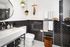 Chic and modern bathroom with sleek black and white tiles, a stylish circular mirror, and elegant fixtures.