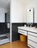 Contemporary bathroom with sleek black tiles, modern white vanity, and elegant glass shower enclosure.