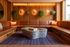 Chic and cozy living room with elegant leather seating, marble coffee table, and warm ambient lighting against a stylish wooden backdrop, featuring lush hanging plants.