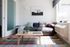 Bright and modern living room with a cozy gray sofa, colorful throw pillows, and a vibrant plaid rug, creating a welcoming ambiance.