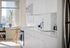 Bright and modern kitchen with sleek white cabinetry, featuring a cozy dining nook and cityscape views.